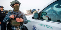 Boarder Patrol agent holds a gun.
