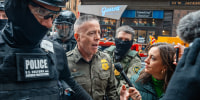U.S. Border Patrol commander Gregory Bovino pushes through a crowd of media and protesters as he enters the Dirksen Federal Building on Oct. 28, 2025, in Chicago.