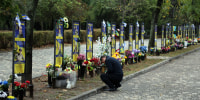 A man places a sign near the monuments with portraits and memorials of fallen Ukrainian Armed Forces on Oct. 1 in Odesa, Ukraine