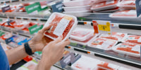 Man Checks Price of Ground Beef at Supermarket.