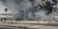 Protesters gather near burning buildings and barricades as clashes erupt in Dar es Salaam on Oct. 29 during Tanzania's presidential elections.