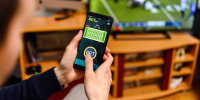 Young men using smart phone for sports betting.