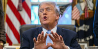 U.S. President Donald Trump speaking while sitting at his desk in the Oval Office.