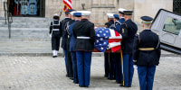 Military body bearers carry the casket.