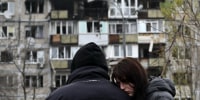 Local residents react in front of a damaged residential building following an air attack in Kyiv on November 29.
