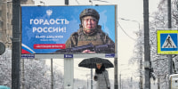 A person walks past a billboard showing a Russian soldier participating in military actions in the Ukraine reading: "The pride of Russia",