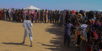 Families line up to receive humanitarian aid at the Al-Afad camp for displaced people on Nov. 25
