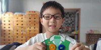 Yuanxin Zheng holding a paper craft t-shirt with buttons attached