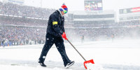 A person shovels snow on a football field