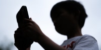 A 7-year-old teenage boy looks at a phone screen on December 7 in Sydney, Australia.