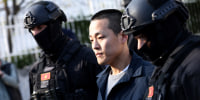 Do Kwon walks between two police officers