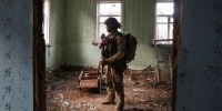 Ukrainian serviceman hides from a Russian combat drone in a building damaged by Russian military strike in the frontline town of Kostiantynivka