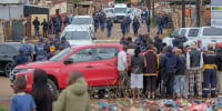 Residents wathch as South African Police Service (SAPS) officers gather at the scene of an attack at a tavern in Bekkersdal on Dec. 21