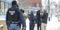 ICE agents question a man outside of a store on a sidewalk, it's snowing