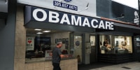 A person walks by a shop for Obamacare insurance