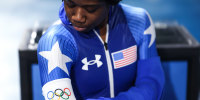 Erin Jackson puts on a white arm band with a graphic showing Olympic rings on it