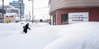 A pedestrian walks on the snow covered pavement 