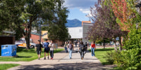 Students walking on Northern Arizona University campus with San Francisco Peaks background