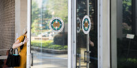 A woman pulling open the glass paneled door of a government office building.