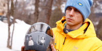 Ukraine's skeleton racer Vladyslav Heraskevych holds his helmet, which depicts victims of his country's war with Russia, in Cortina d'Ampezzo.