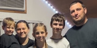 Oksana, second from left, Nikita, right, and their three children pose for a group portrait
