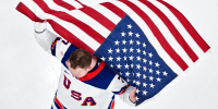 Aerial view of Brady Tkachuk holding an American flag in the air
