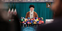 Ayatollah Ali Khamenei  stands in front of dozens of microphones during a press briefing.