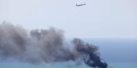 A Middle East Airlines aircraft takes off from the airport in Beirut as smoke rises from the site of an Israeli air strike that targeted an area in the southern suburbs of the Lebanese capital on March 17, 2026.