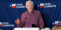 John Cornyn speaks at a lectern with a sign that reads JOHN CORNYN U.S. SENATE.