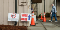 A person walks into a building, signage out front says "vote here"