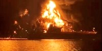 A ship is illuminated by fire from a burning vessel, after Iranian explosive-laden boats appear to have attacked two fuel tankers in Iraqi waters setting them ablaze