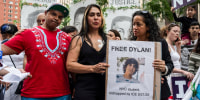 Raiza, center, holds a sign with another woman showing a picture of Dylan Lopez Contreras