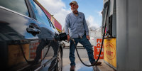 Mike Purcell poses for a portrait while inserting a gas pump into his car's gas tank at Penn Jersey Mart gas station