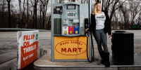Amanda Robbins holds a gas pump at a gas station while posing for a portrait
