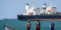 Fishermen pass an oil tanker while on a boat in the water