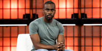Deray Mckesson sits on a white couch on stage