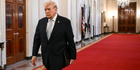 Donald Trump walking on a red carpet at the White House.