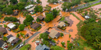 Brown floodwater covers much of a residential neighborhood, seen from an aerial perspective