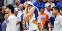 A basketball player hides his head inside his jersey while walking on the court.