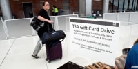 A traveler walks past a gift card donation box for TSA officers
