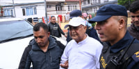 Nepal's former prime minister KP Sharma Oli is escorted by police following his arrest in Kathmandu on March 28.