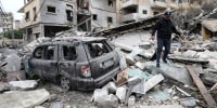 A man walks on the rubble of a destroyed building