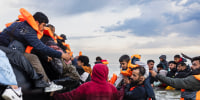 People try to board a smuggler's boat in an attempt to cross the English Channel off the beach of Gravelines, northern France on August 12.