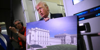 Donald Trump holds a rendering of the East Wing modernization as he speaks to reporters aboard Air Force One en route to Joint Base Andrews, Maryland, on March 29, 2026. 
