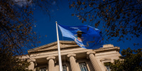 A blue flag flying in front of the DOJ headquarters in Washington.