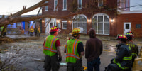 Workers clear fallen trees and debris