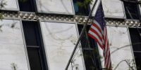 The American flag is displayed outside a non-descript marble building with slender tinted windows.