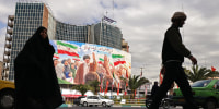 Commuters make their way past a giant billboard of slain Iranian supreme leader Ayatollah Ali Khamenei at the Valiasr Square in Tehran on April 19.