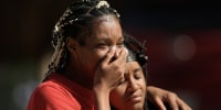 A crying woman covers her mouth with one hand.