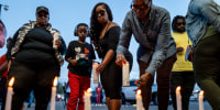 People stand in front of candles lit on the ground outside